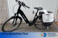 schwarzes Damenpedelec Cube mit tiefem Einstieg und einer Doppelsatteltasche in grau